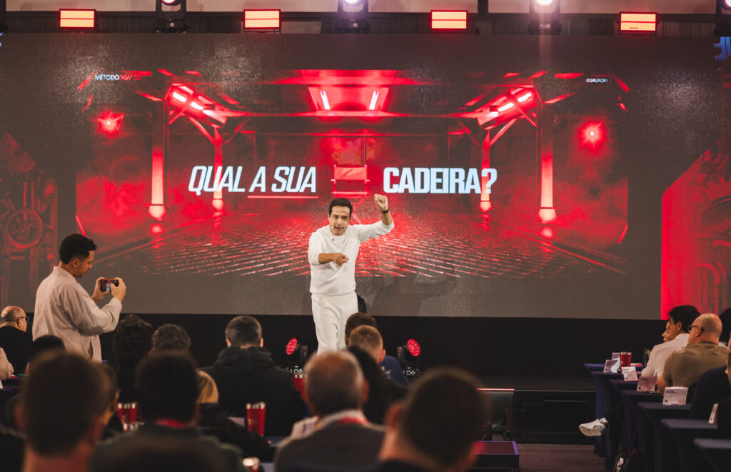 Palco do RGV 40 com painel de LED exibindo conteúdo e plateia de empresários