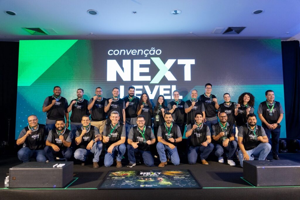 Participantes com medalhas diante do painel da convenção.