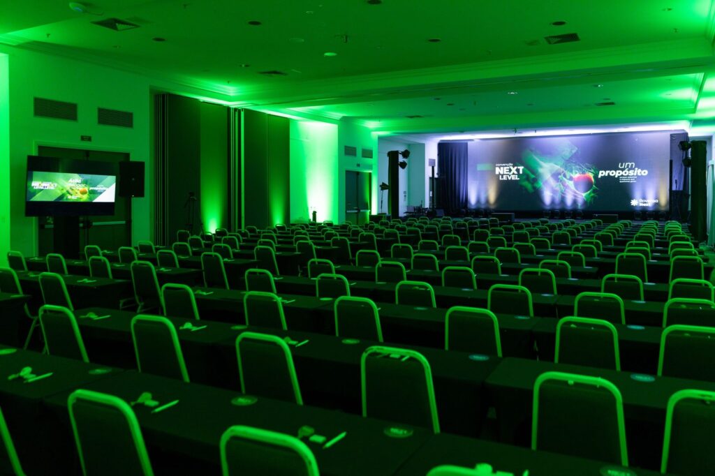 Sala preparada para a Convenção Rovensa Next, com painel de LED e iluminação.